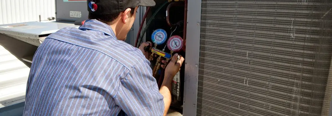 HVAC technician servicing a condenser unit in Henderson