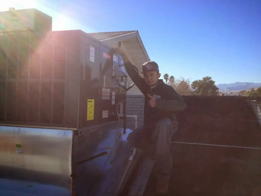 HVAC technician performing Boiler Repair on a rooftop unit in Henderson